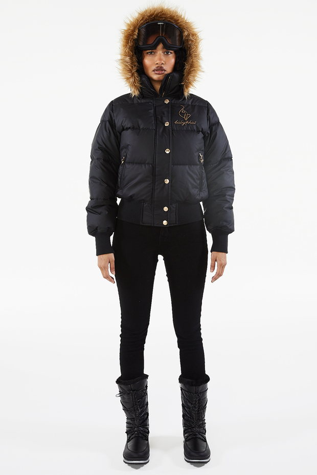 Baby Phat reissue OG puffer jacket in onyx is a matte black jacket that features a faux fur trim hood, cat logo detailing on the front and back, gold buttons, and a cat zipper pull.