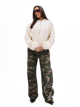 Zip up sweatshirt with gothic applique, cream zip-front hoodie with camouflage pants, on-model full-body front view