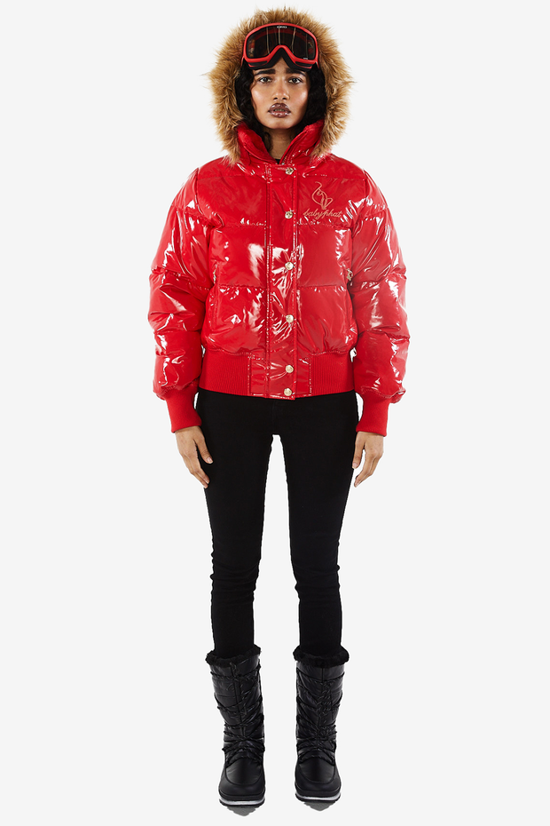 Baby Phat reissue OG puffer jacket in gloss red is a glossy red lacquer jacket that features a faux fur trim hood, cat logo detailing on the front and back, gold buttons, and a cat zipper pull.
