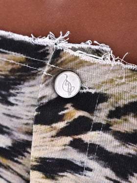 Low Waist Raw Edge Denim Skirt in Animal Print, frayed waistband and logo button, close-up detail