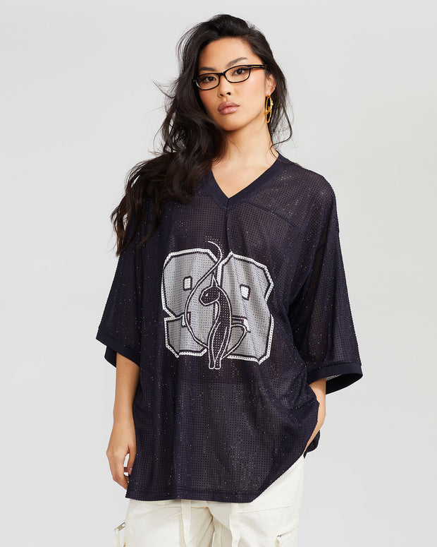 Standard sized model shown wearing semi sheer black oversized jersey with black rhinestones all over. Jersey features grey 99 cat logo large at center front with grey all over rhinestones.  Jersey features v-neckline. Model is also wearing off white cargo pants and glasses.