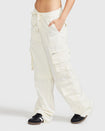 Side view image of standard sized model’s legs wearing off white cargo pant with tied waist and belt loops. Pants feature exaggerated pocket detailing down both legs and large pockets on both sides of rear. Hidden zippers below the knees. 