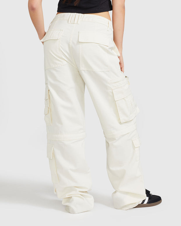 Back view image of standard sized model’s legs wearing off white cargo pant with visible belt loops. Pants feature exaggerated pocket detailing down both legs and large pockets on both sides of rear. Hidden zippers below the knees. 