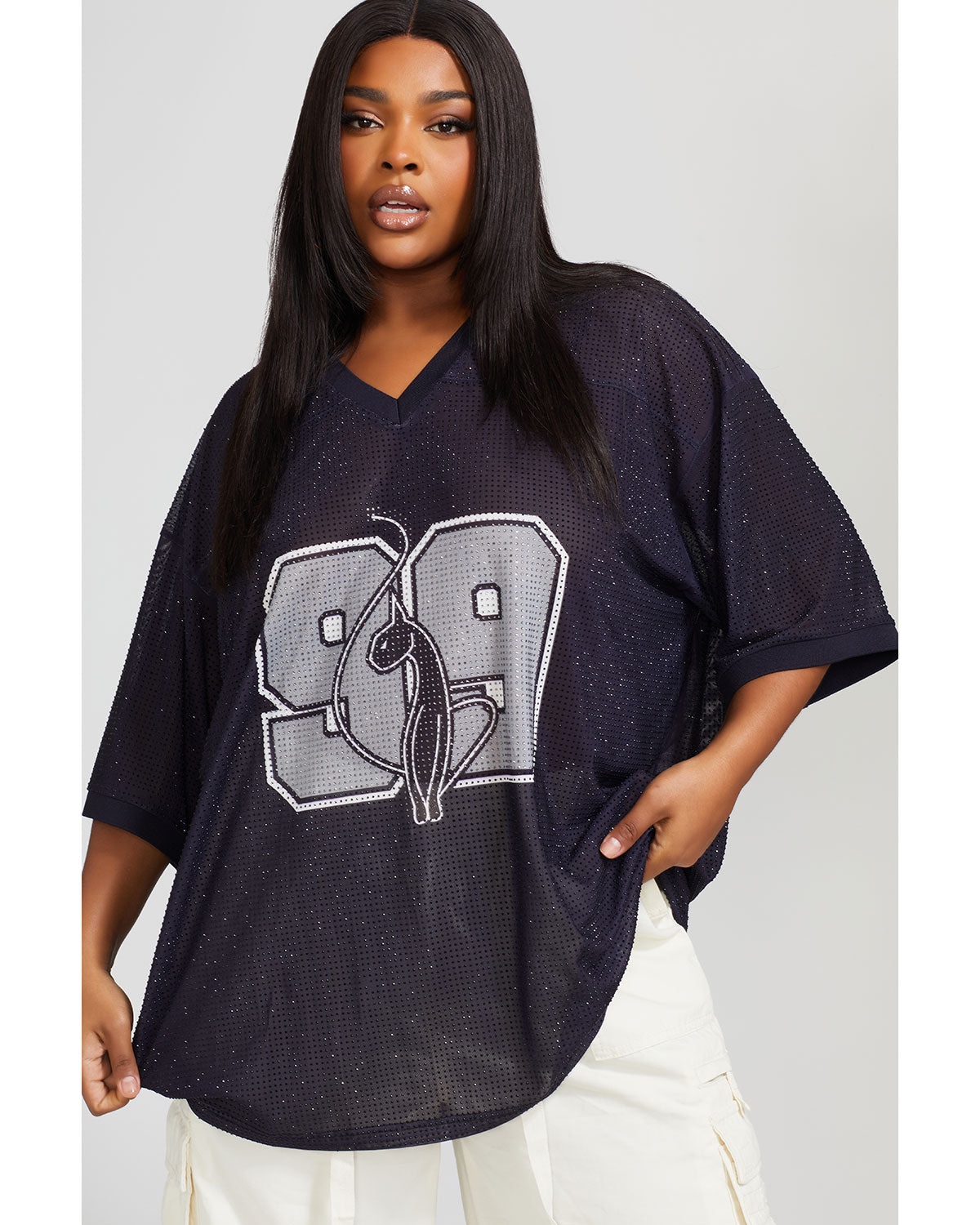 Plus sized model shown wearing semi sheer black oversized jersey with black rhinestones all over. Jersey features grey 99 cat logo large at center front with grey all over rhinestones.  Jersey features v-neckline. Model is also wearing off white cargo pants.