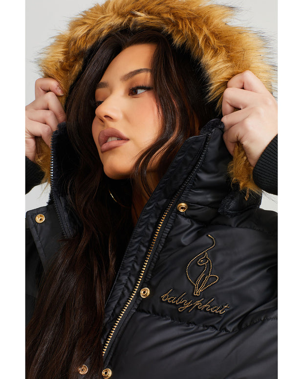 Model shown wearing black puffer jacket. Coat features natural faux fur trimmed detachable hood and Baby Phat script logo on front chest and oversized cat logo on the back. Jacket also features gold cat logo zipper pulls on the front pockets and center front.