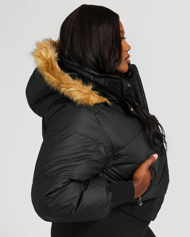 Plus sized model shown wearing black puffer jacket. Coat features natural faux fur trimmed detachable hood and Baby Phat script logo on front chest and oversized cat logo on the back. Jacket also features gold cat logo zipper pulls on the front pockets and center front.