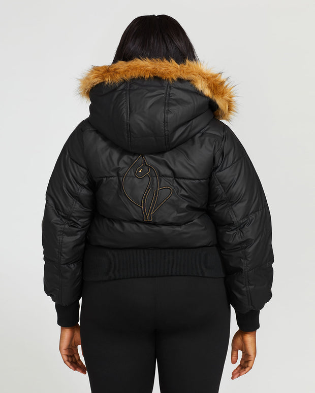 Plus sized model shown wearing black puffer jacket. Coat features natural faux fur trimmed detachable hood and Baby Phat script logo on front chest and oversized cat logo on the back. Jacket also features gold cat logo zipper pulls on the front pockets and center front.