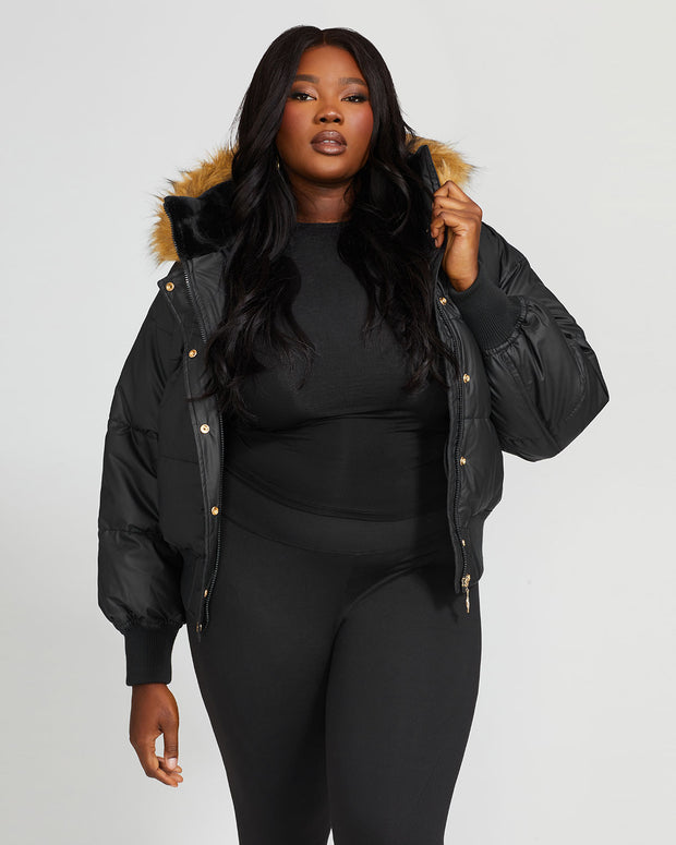 Plus sized model shown wearing black puffer jacket. Coat features natural faux fur trimmed detachable hood and Baby Phat script logo on front chest and oversized cat logo on the back. Jacket also features gold cat logo zipper pulls on the front pockets and center front.