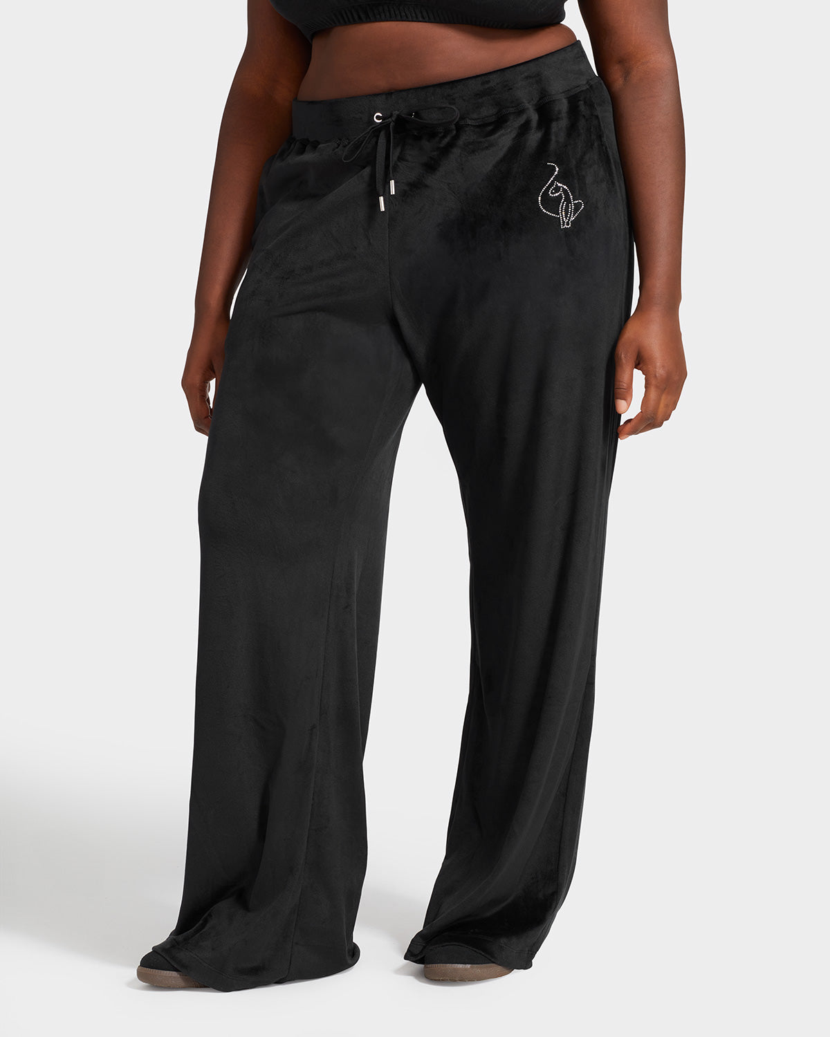 Plus sized model shown wearing black velour sweatpants. Pants feature a wide leg, open bottom fit with a rhinestone Baby Phat cat logo on the wearer's left upper thigh. Pants feature pockets and an elastic waistband with a drawstring tie.