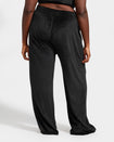 Plus sized model shown wearing black velour sweatpants. Pants feature a wide leg, open bottom fit with a rhinestone Baby Phat cat logo on the wearer's left upper thigh. Pants feature pockets and an elastic waistband with a drawstring tie.