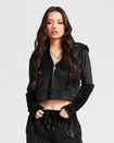 Standard sized model shown wearing black velour zip up hoodie with matching wide leg sweatpants. Zippered sweatshirt features rhinestone Baby Phat script logo on upper chest and oversized rhinestone cat logo on the back. Sweatshirt features silver cat logo zipper pull.
