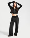 Standard sized model shown wearing black velour sweatpants with matching zip up hooded sweatshirt. Pants feature a wide leg, open bottom fit with a rhinestone Baby Phat cat logo on the wearer's left upper thigh. Pants feature pockets and an elastic waistband with a drawstring tie.