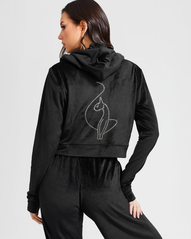 Back view image of standard sized model shown wearing black velour zip up hoodie with matching wide leg sweatpants. Zippered sweatshirt features rhinestone Baby Phat script logo on upper chest and oversized rhinestone cat logo on the back. Sweatshirt features silver cat logo zipper pull.