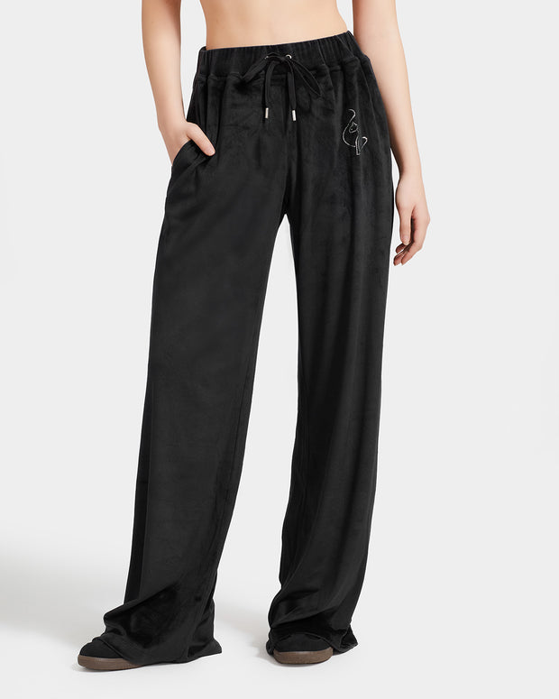 Standard sized model shown wearing black velour sweatpants. Pants feature a wide leg, open bottom fit with a rhinestone Baby Phat cat logo on the wearer's left upper thigh. Pants feature pockets and an elastic waistband with a drawstring tie.