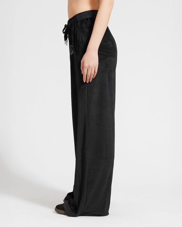 Standard sized model shown wearing black velour sweatpants. Pants feature a wide leg, open bottom fit with a rhinestone Baby Phat cat logo on the wearer's left upper thigh. Pants feature pockets and an elastic waistband with a drawstring tie.