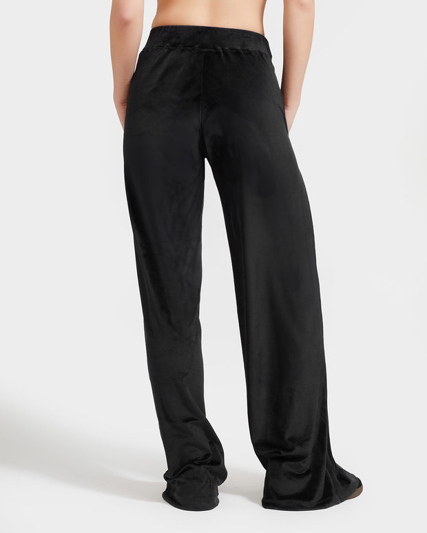 Standard sized model shown wearing black velour sweatpants. Pants feature a wide leg, open bottom fit with a rhinestone Baby Phat cat logo on the wearer's left upper thigh. Pants feature pockets and an elastic waistband with a drawstring tie.