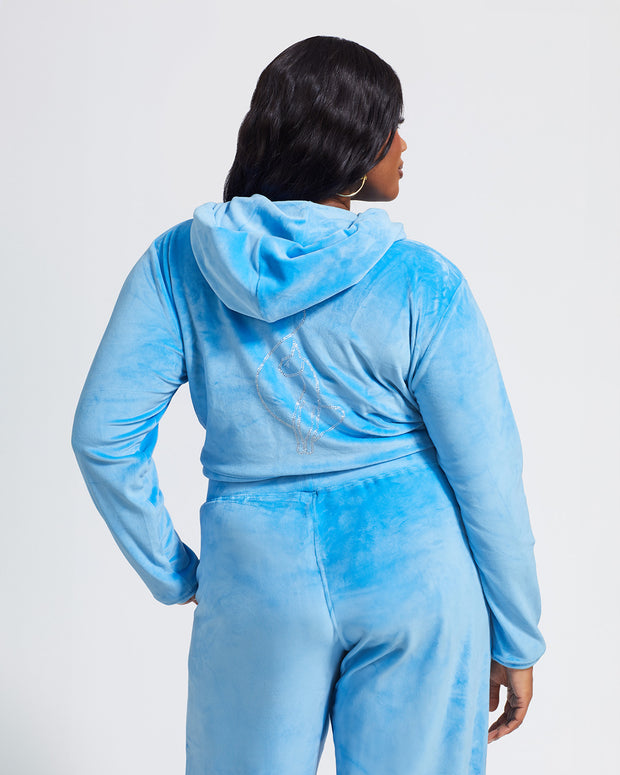 Back view image of plus sized model shown wearing blue velour zip up hoodie with matching wide leg sweatpants. Zippered sweatshirt features rhinestone Baby Phat script logo on upper chest and oversized rhinestone cat logo on the back. Sweatshirt features silver cat logo zipper pull.