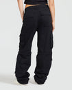 Back view image of standard sized model’s legs wearing black cargo pant with visible belt loops. Pants feature exaggerated pocket detailing down both legs and large pockets on both sides of rear. Hidden zippers below the knees. 