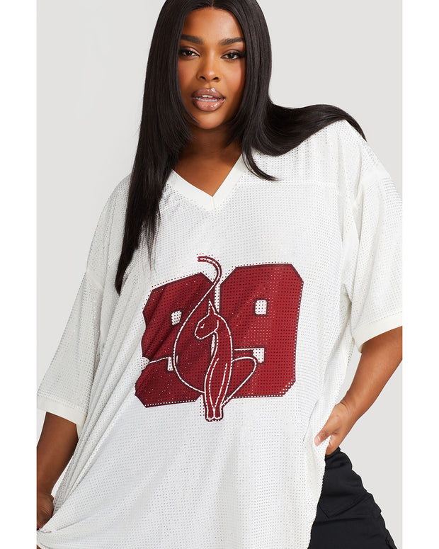 Plus sized model shown wearing off white oversized jersey with clear rhinestones all over. Jersey features burgundy 99 cat logo large at center front with burgundy all over rhinestones.  Jersey features v-neckline. Model is also wearing black cargo pants.