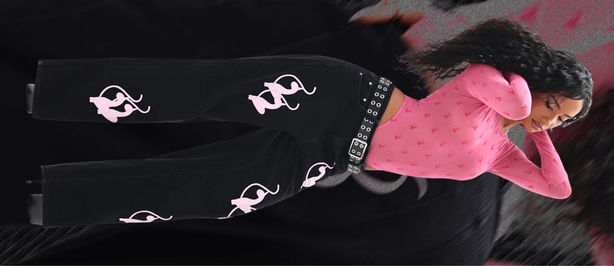 Model in baggy black jeans and a pink mesh body suit.