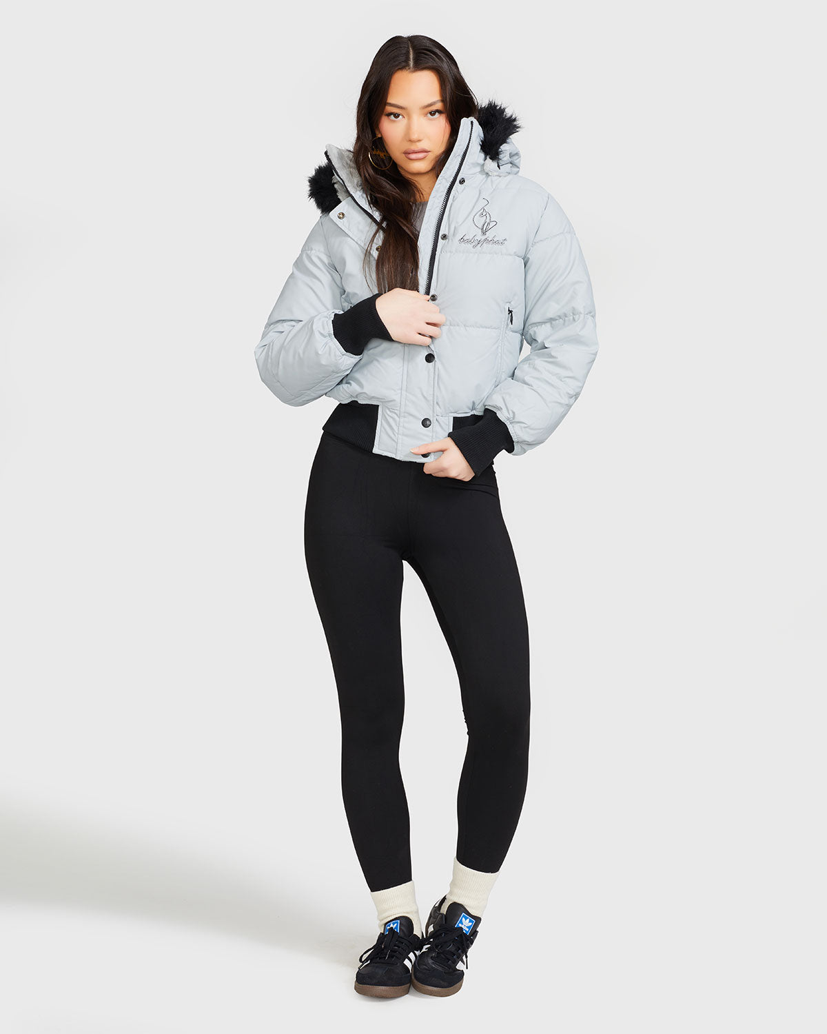 Model shown wearing light grey smoke puffer jacket. Coat features black faux fur detachable hood and Baby Phat script logo on front chest and oversized cat logo on the back. Jacket also features gold cat logo zipper pulls on the front pockets and center front.