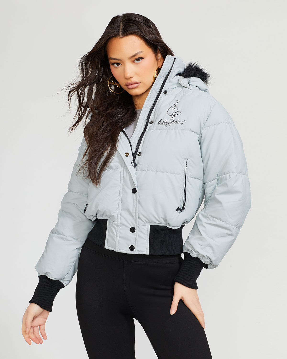 Model shown wearing light grey smoke puffer jacket. Coat features black faux fur detachable hood and Baby Phat script logo on front chest and oversized cat logo on the back. Jacket also features gold cat logo zipper pulls on the front pockets and center front.