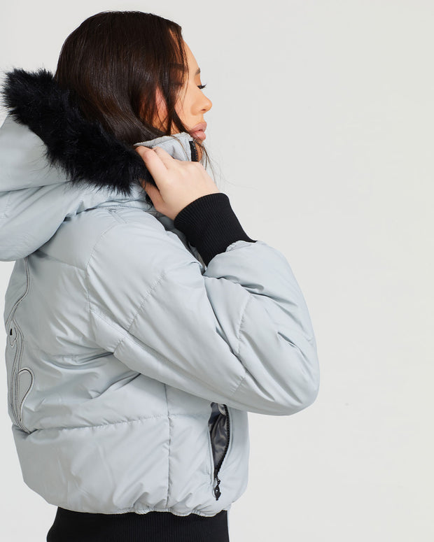 Model shown wearing light grey smoke puffer jacket. Coat features black faux fur detachable hood and Baby Phat script logo on front chest and oversized cat logo on the back. Jacket also features gold cat logo zipper pulls on the front pockets and center front.