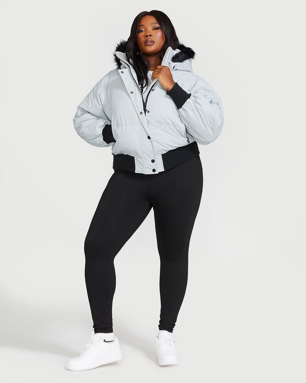 Plus sized model shown wearing light grey smoke puffer jacket. Coat features black faux fur detachable hood and Baby Phat script logo on front chest and oversized cat logo on the back. Jacket also features gold cat logo zipper pulls on the front pockets and center front.