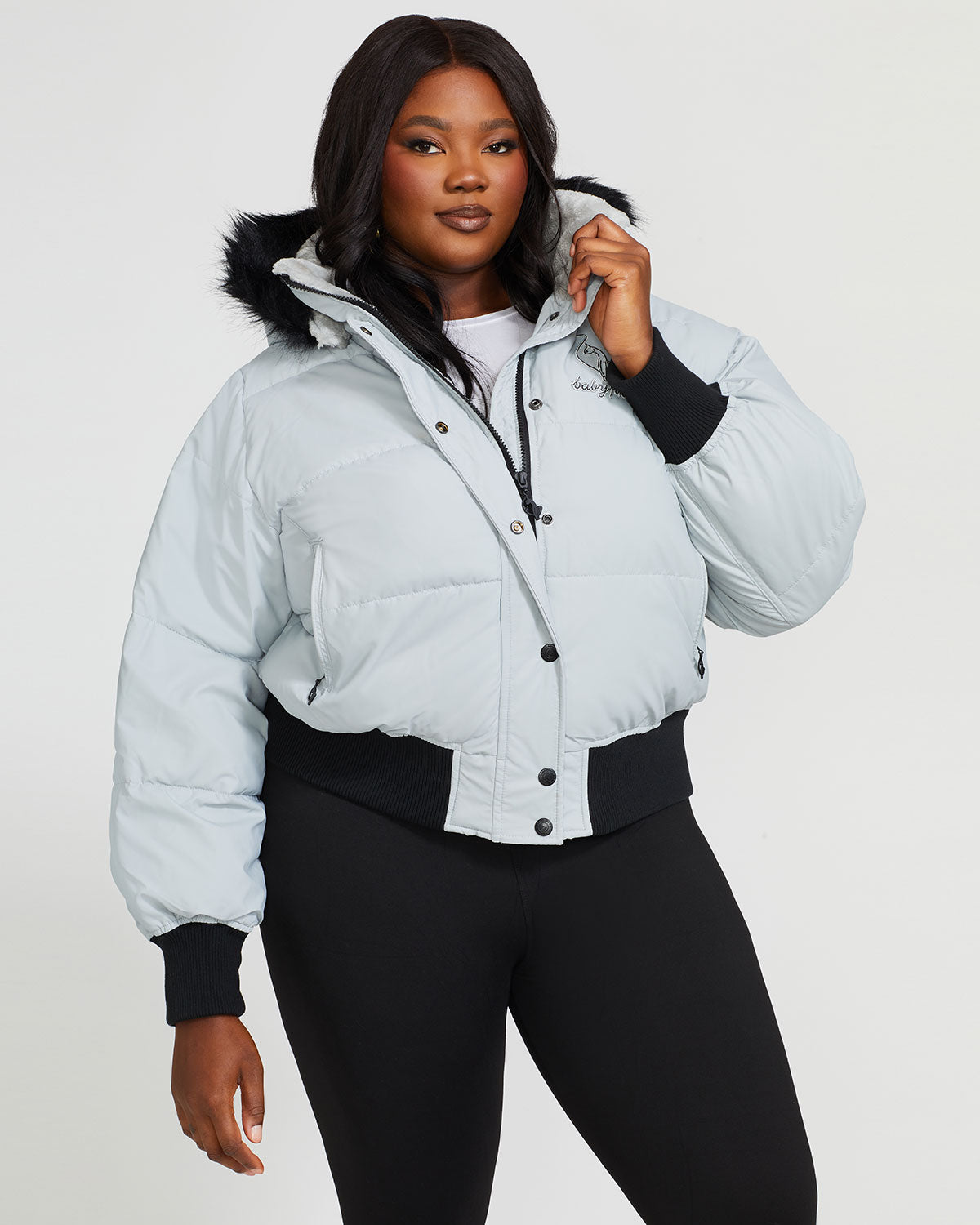 Plus sized model shown wearing light grey smoke puffer jacket. Coat features black faux fur detachable hood and Baby Phat script logo on front chest and oversized cat logo on the back. Jacket also features gold cat logo zipper pulls on the front pockets and center front.