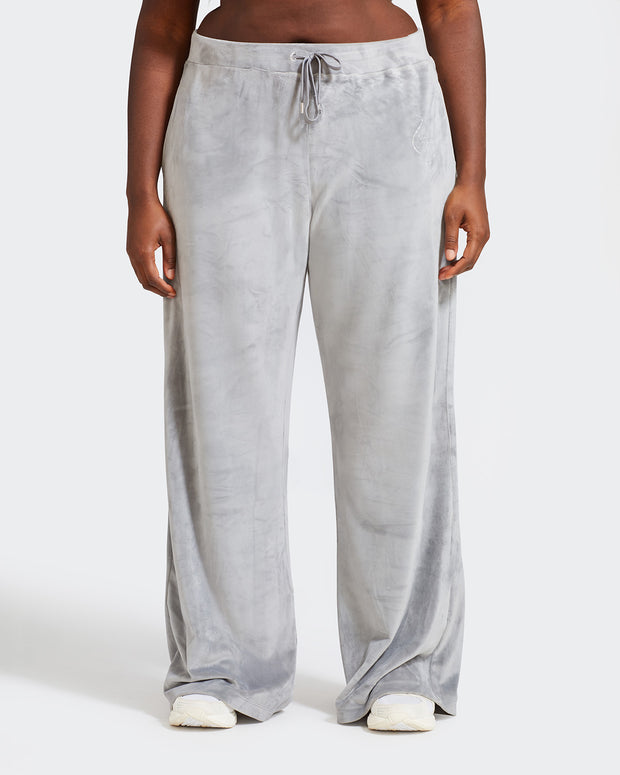 Plus sized model shown wearing grey velour sweatpants. Pants feature a wide leg, open bottom fit with a rhinestone Baby Phat cat logo on the wearer's left upper thigh. Pants feature pockets and an elastic waistband with a drawstring tie.