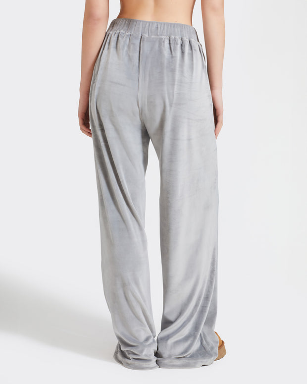 Back view image of standard sized model shown wearing grey velour sweatpants. Pants feature a wide leg, open bottom fit with a rhinestone Baby Phat cat logo on the wearer's left upper thigh. Pants feature pockets and an elastic waistband with a drawstring tie.