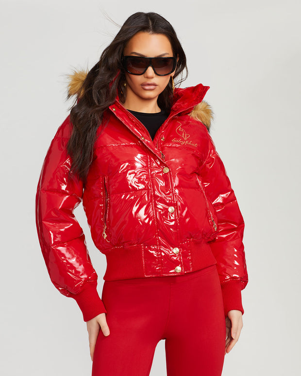 Model shown wearing glossy red puffer jacket. Coat features natural faux fur trimmed detachable hood and Baby Phat script logo on front chest and oversized cat logo on the back. Jacket also features gold cat logo zipper pulls on the front pockets and center front.