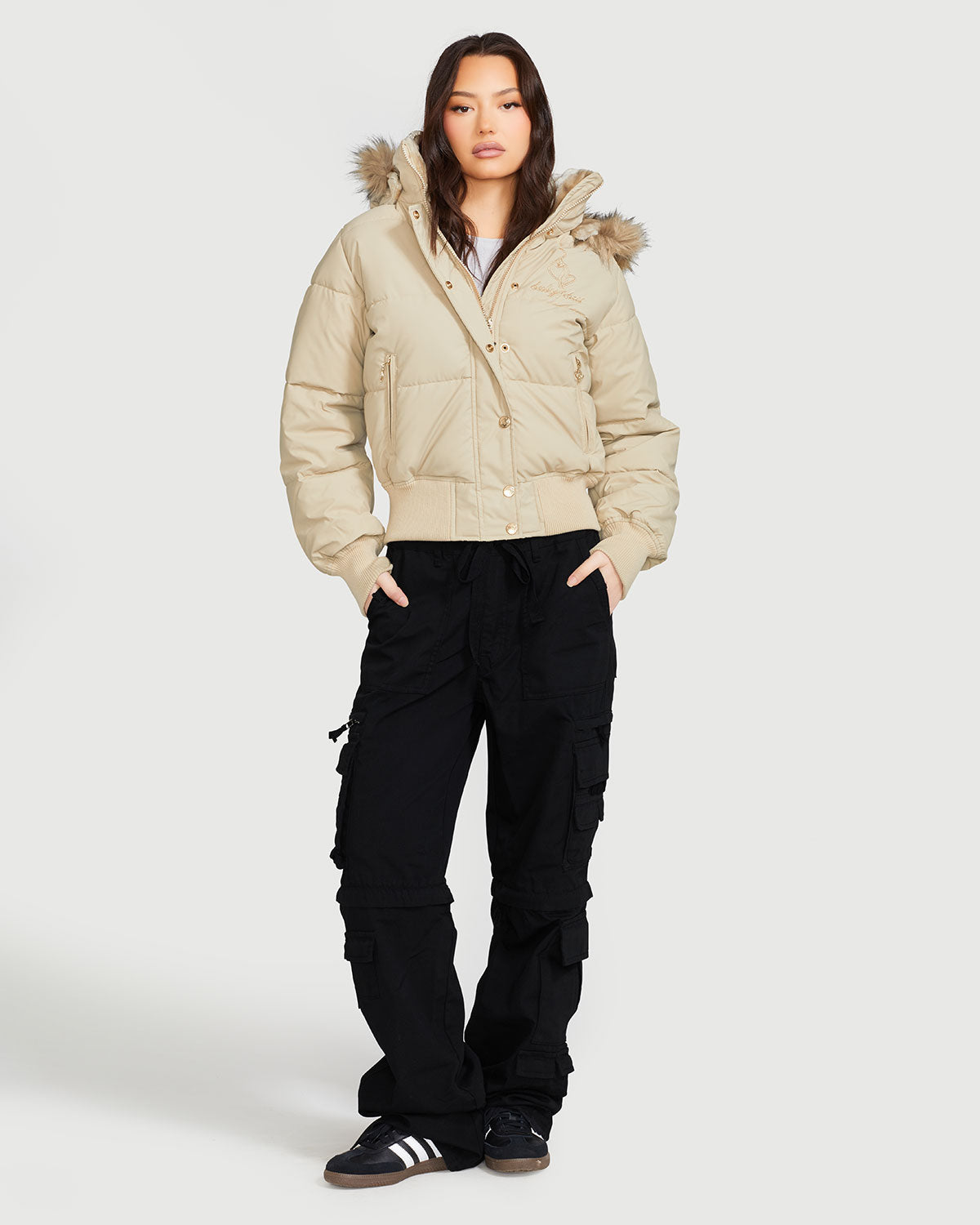 Model shown wearing light tan puffer jacket. Coat features natural faux fur trimmed detachable hood and Baby Phat script logo on front chest and oversized cat logo on the back. Jacket also features gold cat logo zipper pulls on the front pockets and center front.