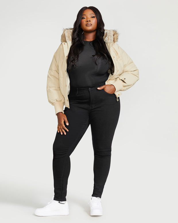 Plus sized model shown wearing light tan puffer jacket. Coat features natural faux fur trimmed detachable hood and Baby Phat script logo on front chest and oversized cat logo on the back. Jacket also features gold cat logo zipper pulls on the front pockets and center front.