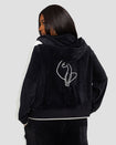 Back view image of plus sized model wearing black velour zip up hoodie with color blocked off white panel down both sleeves. Zippered sweatshirt features matching black ribbing at the wrists and hem with off white tipping. Large embroidered cat logo on center back. Model is also wearing matching black sweatpant with off white color blocking. 