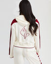 Back view image of standard sized model wearing off white velour zip up hoodie with color blocked burgundy panel down both sleeves. Zippered sweatshirt features matching off white ribbing at the wrists and hem with burgundy tipping. Embroidered large cat logo on center back. Model is also wearing matching off white sweatpant with burgundy color blocking. 