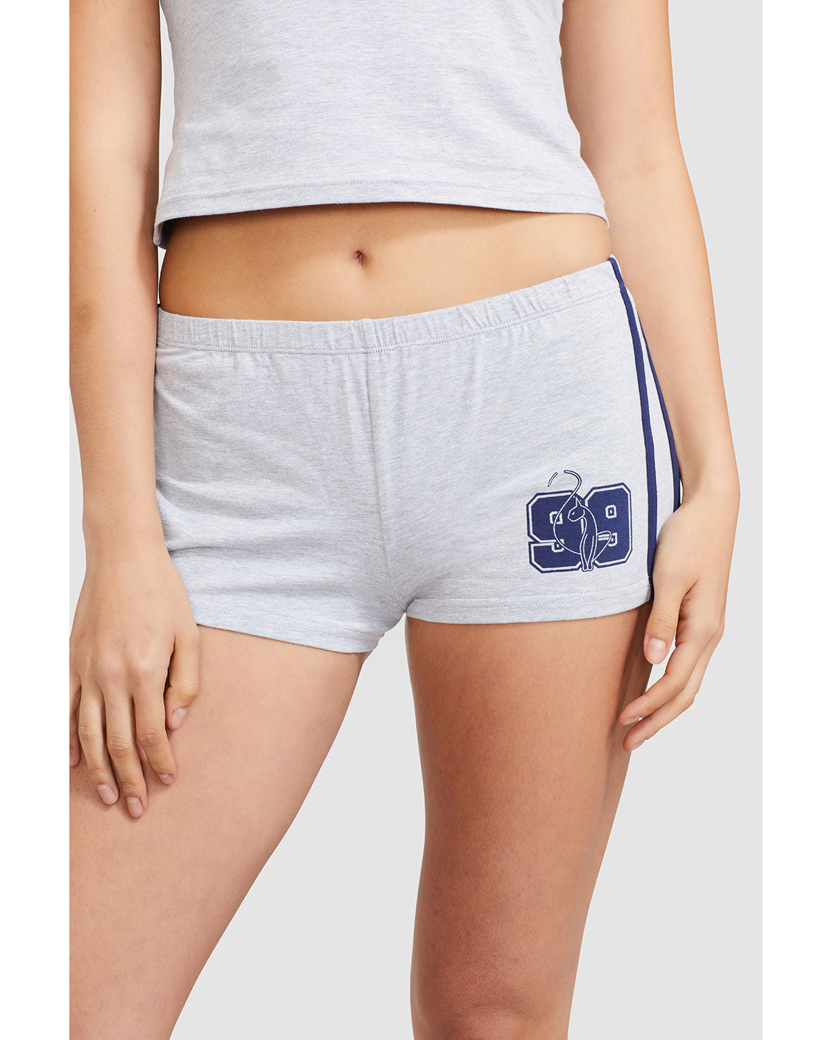 Standard sized model’s torso and legs shown wearing heather grey micro short with 2 contrasting navy blue stripes down both sides. Short features navy blue Baby Phat cat 99 heritage logo on wearer's left thigh. 
