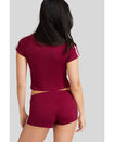 Back view image shows standard sized model shown wearing burgundy baby tee shirt with cream stripes on the shoulder. Model is also wearing matching burgundy micro shorts.